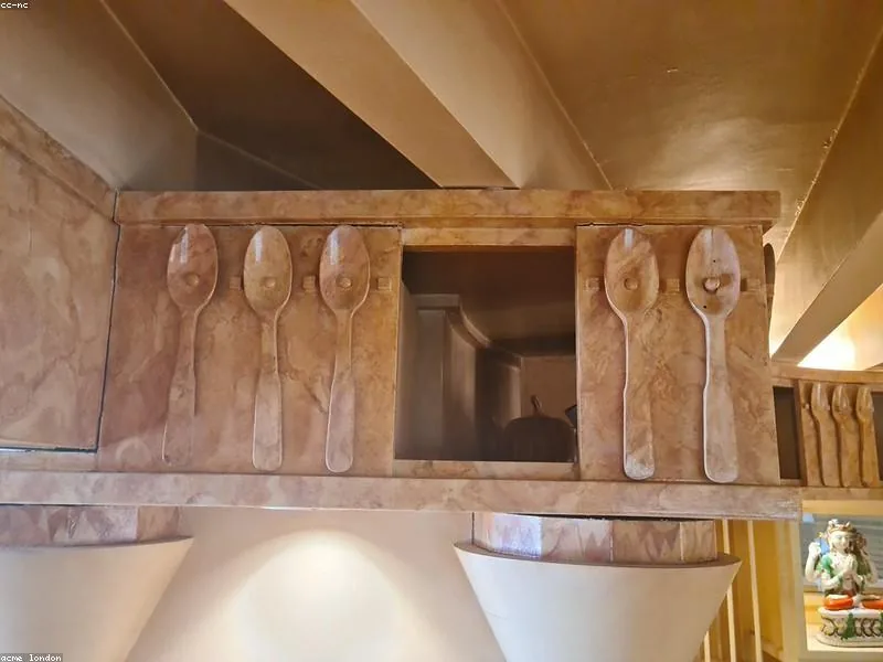 Keuken met lichtgroene kasten, gepolijst marmeren werkblad en messing kraan